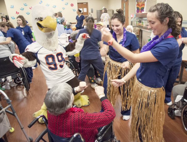 Jefferson County Nursing Home resident Anna Sinard (center) dances with Carson-Newman mascot, Talon, and C-N sophomore nursing students, Alyssa Koster, left, and Catherine Hunley, right, during the end of semester luau students held for residents.