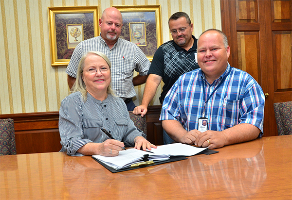 Marty Chambers, Carson-Newman University's chief financial officer, front left, sits with Mitch Cain of Appalachian Electric Cooperative as the two sign a contract making the University the first organization in Jefferson County to join the new Demand Response Program.  Chambers and Cain are joined by Ondes Webster, back left, and Steve Finchum of C-N's Physical Plant.