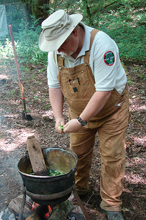 TWRA Region 4 Wildlife Program Coordinator Pete Wyatt prepares wild game stew in a copper pot over an open fire and one of his signature fruit cobblers on a Dutch oven.