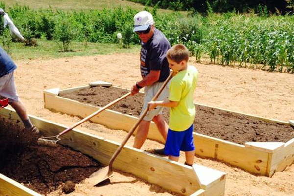 ASEC member, George Giles, helps young Thomas fill a raised bed.