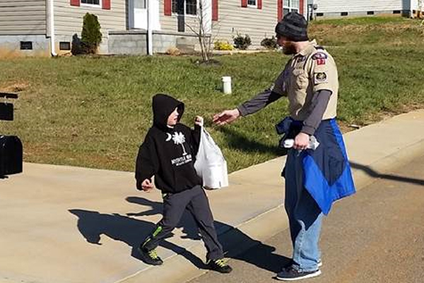 Thomas Will, Bear Cub, handing CubMaster Chad Thompson bags of food collected for the Dandridge Ministerial Association’s Food Pantry.