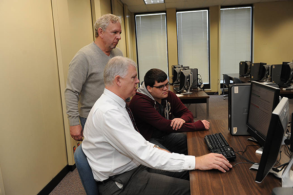 Dr. Tom Sewell, dean of technical education, center, shares some programming tips with Treyton Williams, associate professor of computer science, and student Doug Bolton. Bolton’s volunteer internship has turned into a paying job.