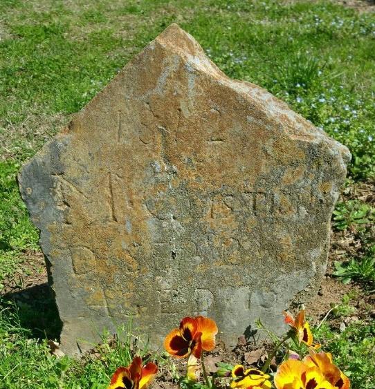 Original, rough-hewn gravestone on the grave of Patriot James McCuistion.  The new gray granite marker will lie flat over the grave and honor his service in the Revolutionary War.